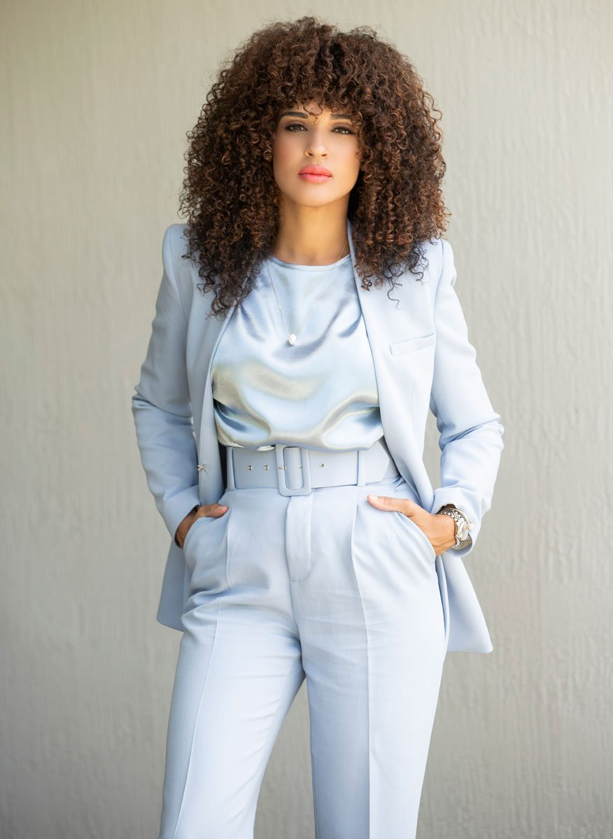 A female attorney with curly hair is wearing a light blue suit.