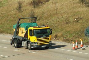 A lorry with a skip on the back on the motorway