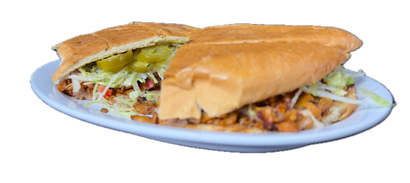 A sub sandwich cut in half on a white plate, filled with lettuce, pickles, and meat.