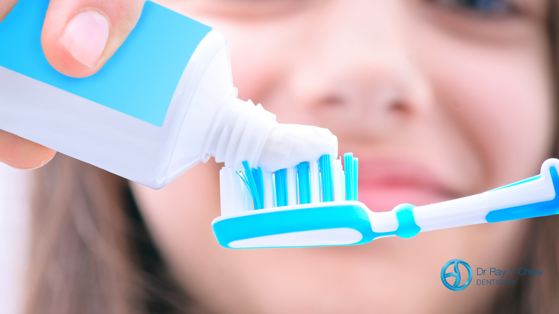 Person squeezing toothpaste onto a blue toothbrush.