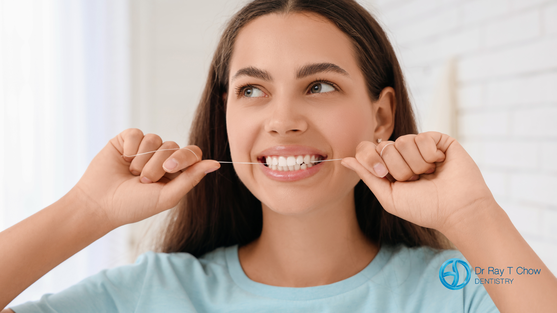 Smiling woman in a light blue shirt showing her teeth with raised fists in a bright room