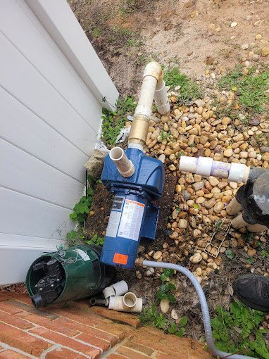 A water pump is sitting on the ground next to a brick wall.