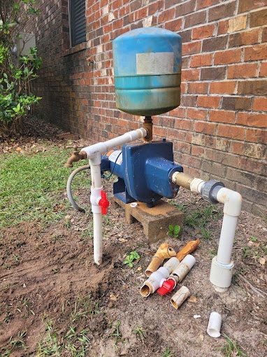 A water pump is sitting next to a brick wall.