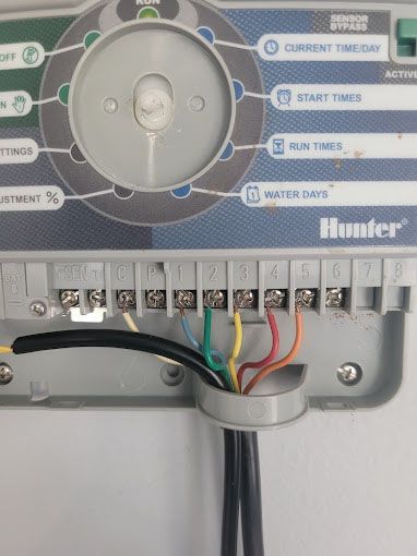 A close up of a hunter irrigation controller with wires connected to it.
