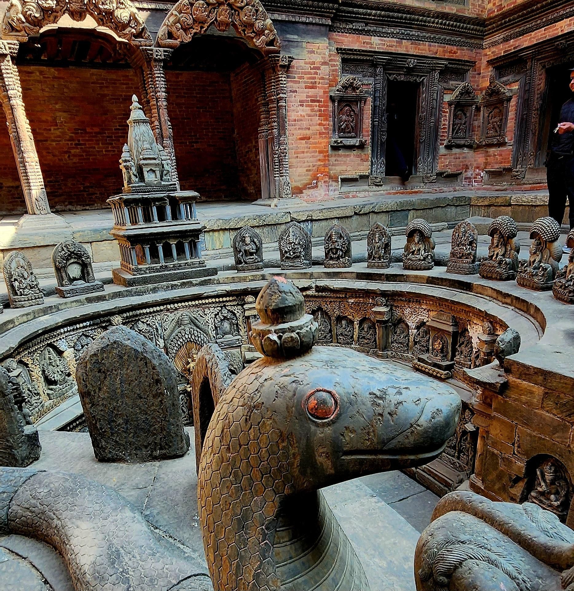 A statue of a snake with a red eye is surrounded by other statues