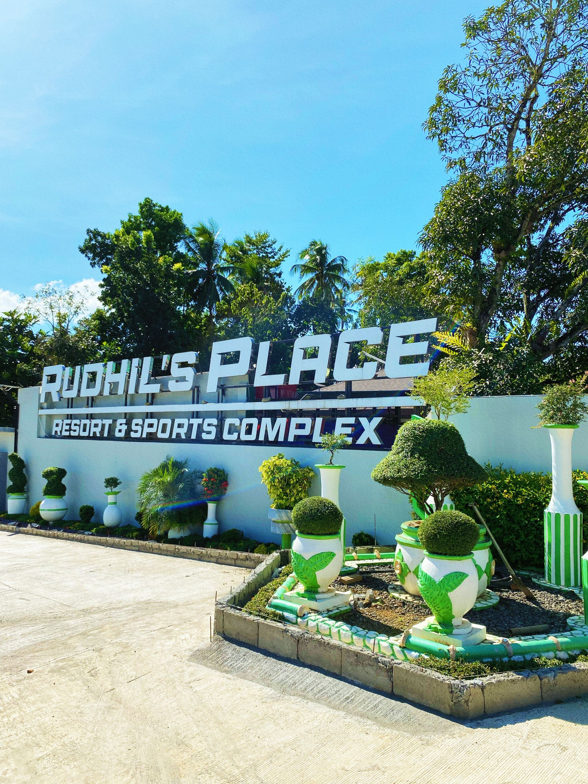 A sign for rudhil 's place resort & sports complex