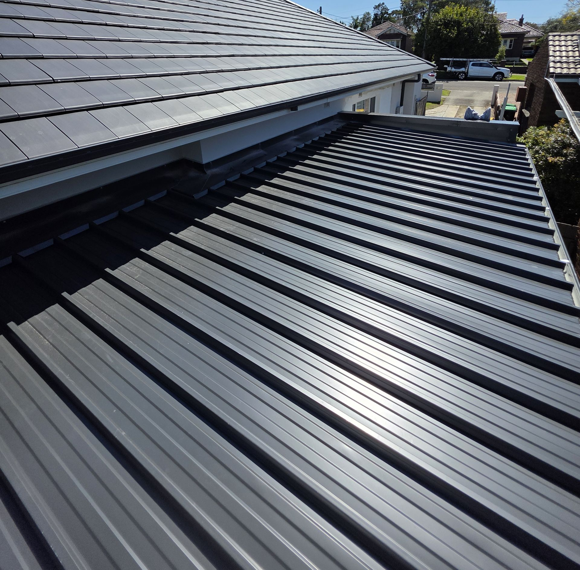 Dark Gray Tiled Roof Against a Cloudy Blue Sky — McLuckie Metal Roofing In Lugarno, NSW