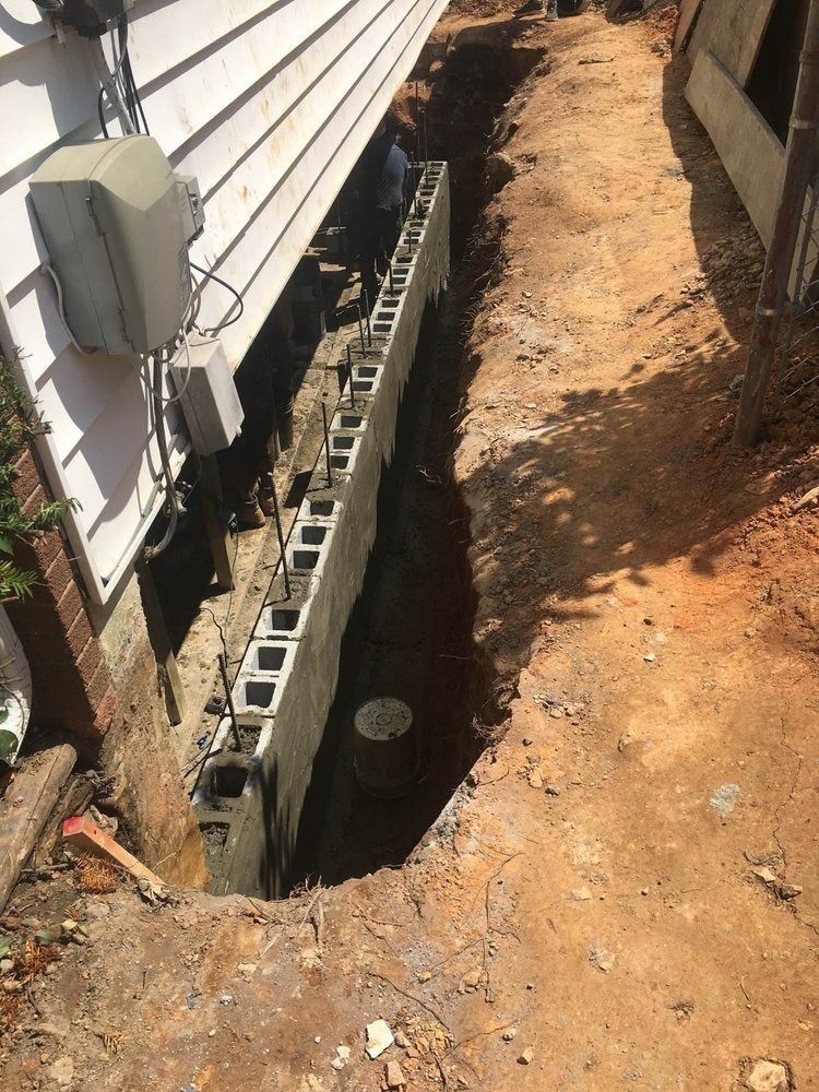 A concrete block wall is being built on the side of a house.
