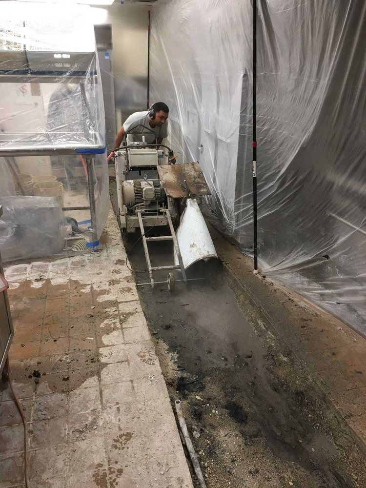 A man is cutting concrete with a machine in a room.