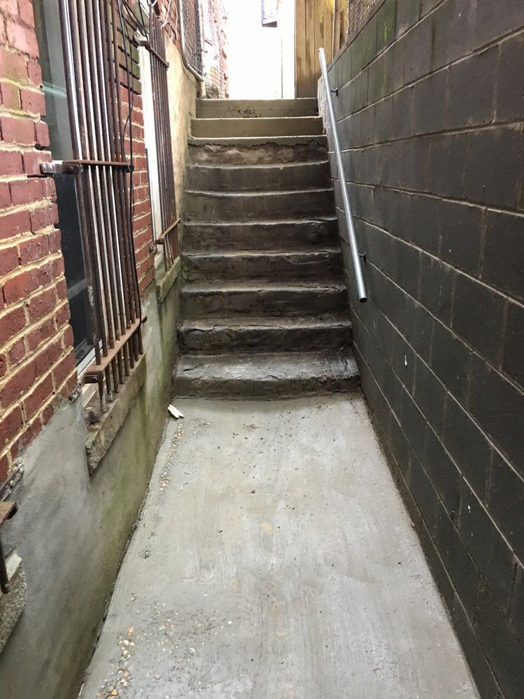 A narrow alleyway with stairs leading up to a building.
