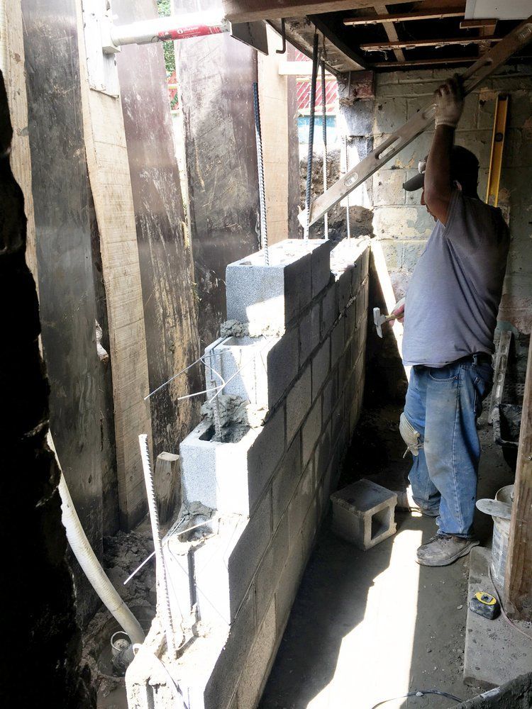 A man is working on a brick wall in a basement