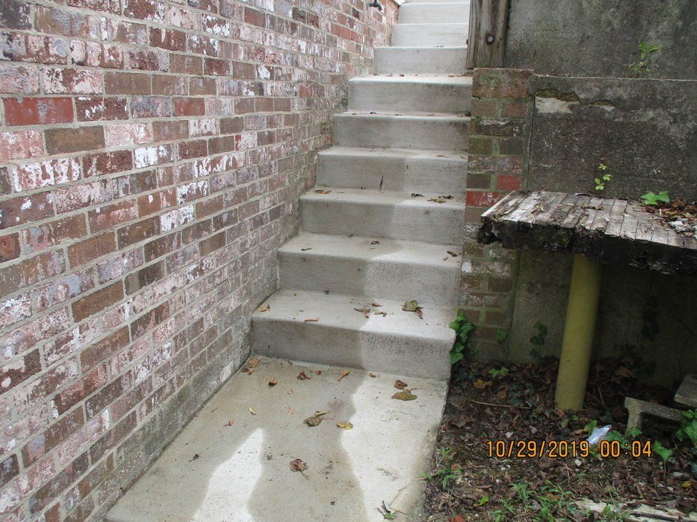 A set of concrete stairs leading up to a brick wall