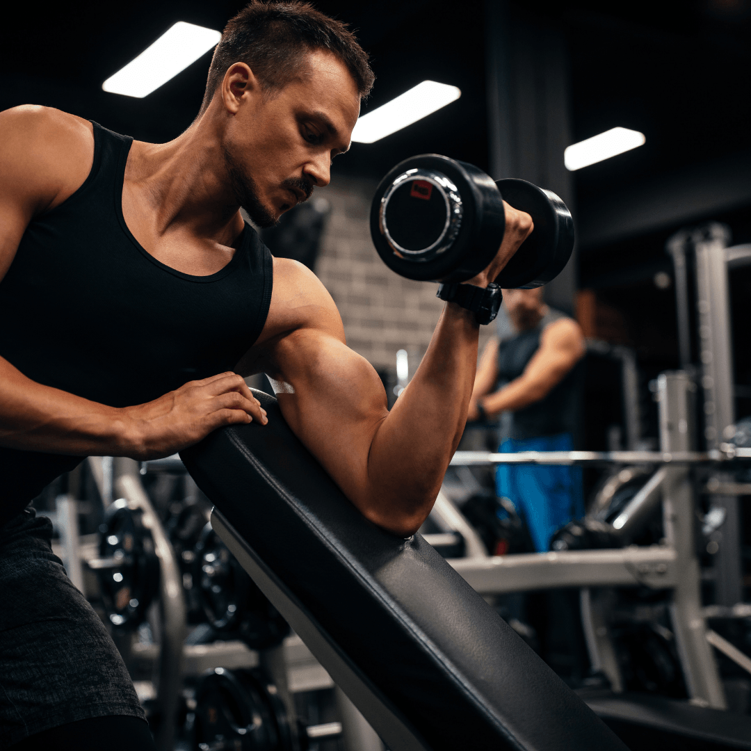 A man is lifting a dumbbell in a gym