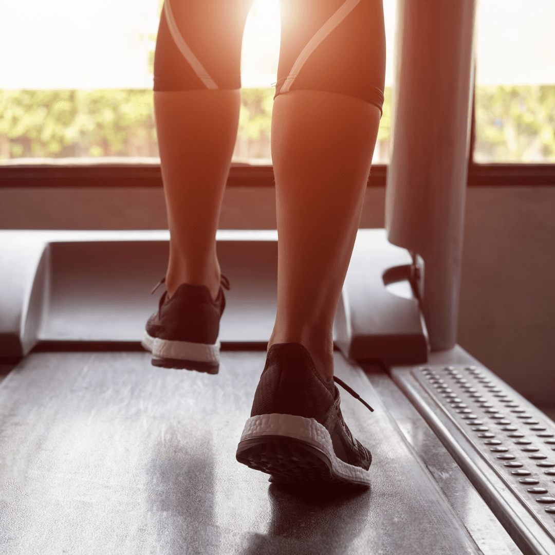 A person is walking on a treadmill in a gym.