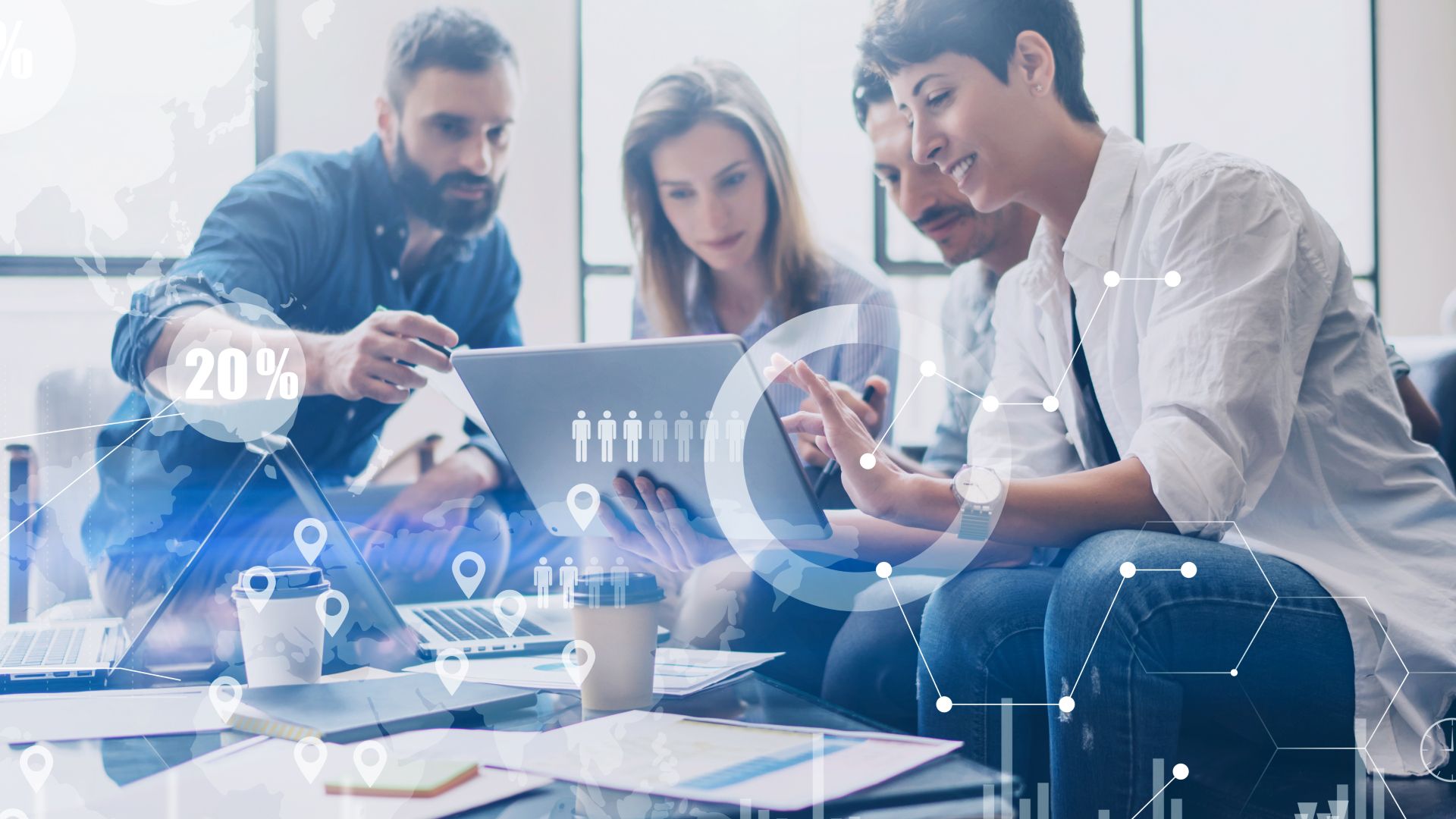 A group of people are sitting around a table looking at a laptop.