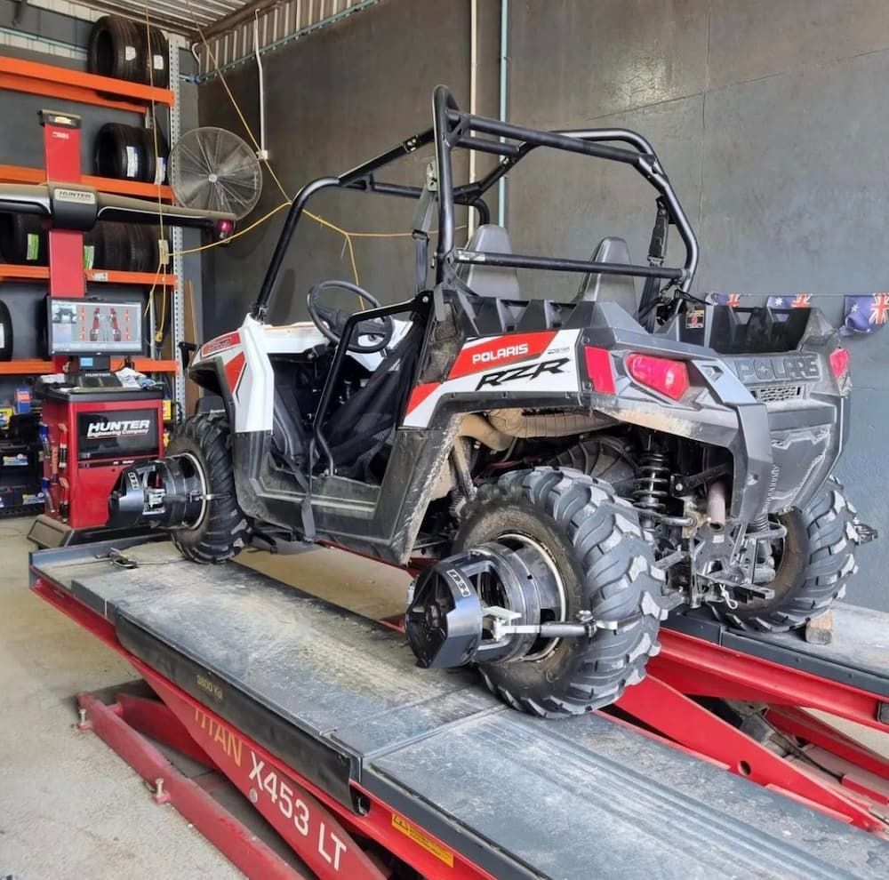 A Polaris Rzr is Sitting on a Lift in a Garage — Tyrepower Innisfail In Goondi Bend, QLD