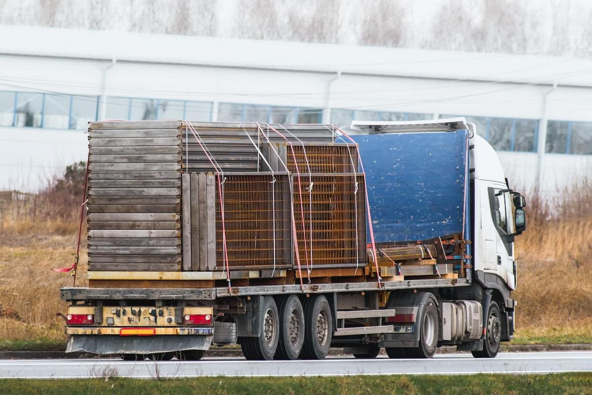 A Truck Is Driving Down A Road With A Blue Tarp On The Back Of It — Tyrepower Innisfail In Cardwell, QLD