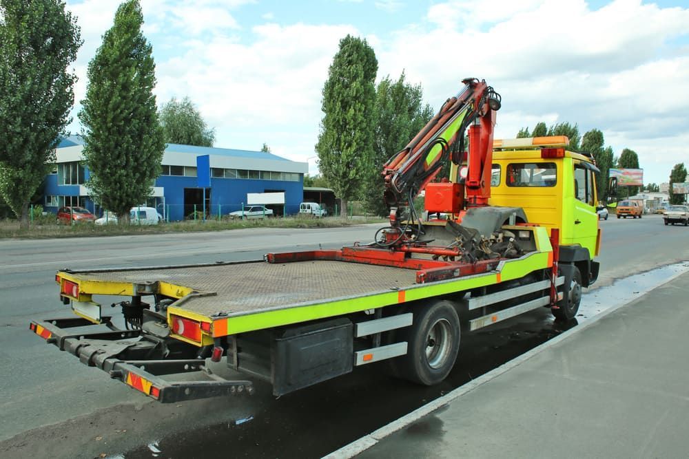 A Yellow Tow Truck With A Crane On The Back Is Parked On The Side Of The Road — Tyrepower Innisfail In Goondi Bend, QLD