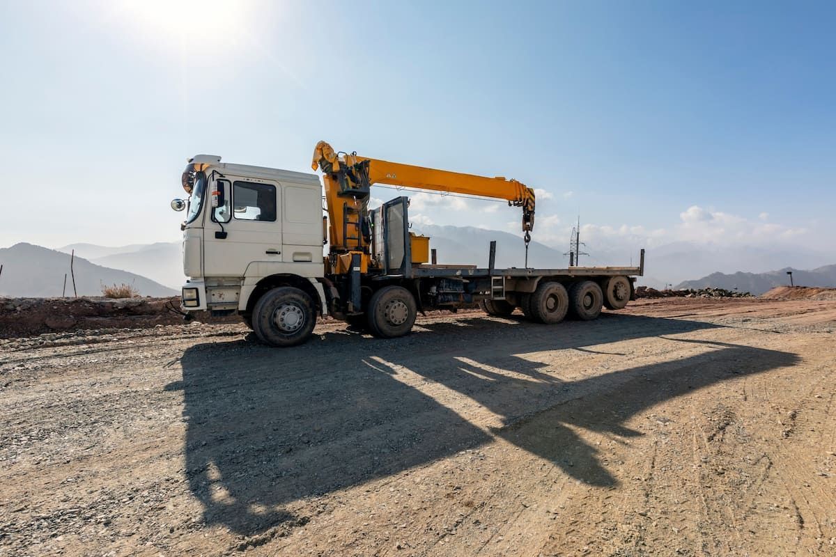 A White Truck With A Yellow Crane On The Back Is Parked On A Dirt Road — Tyrepower Innisfail In Babinda, QLD