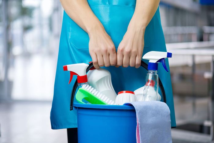 Cleaning supplies bucket with spray bottles and brushes for professional cleaning service.