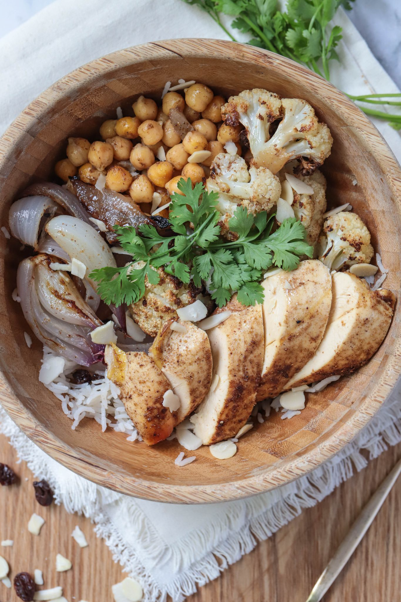Chicken and veggie bowl with chickpeas, cauliflower, and onions in a wooden bowl.
