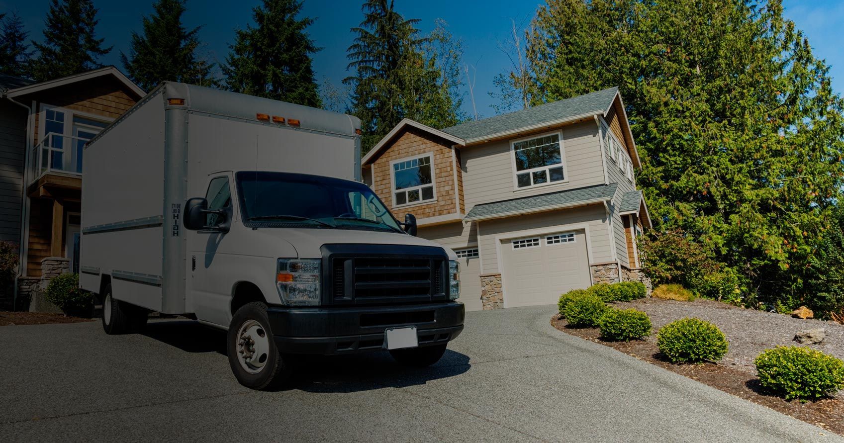 A white moving truck is parked in front of a house.