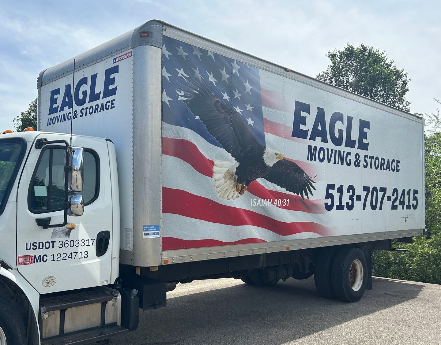 A white moving truck is parked in front of a house.