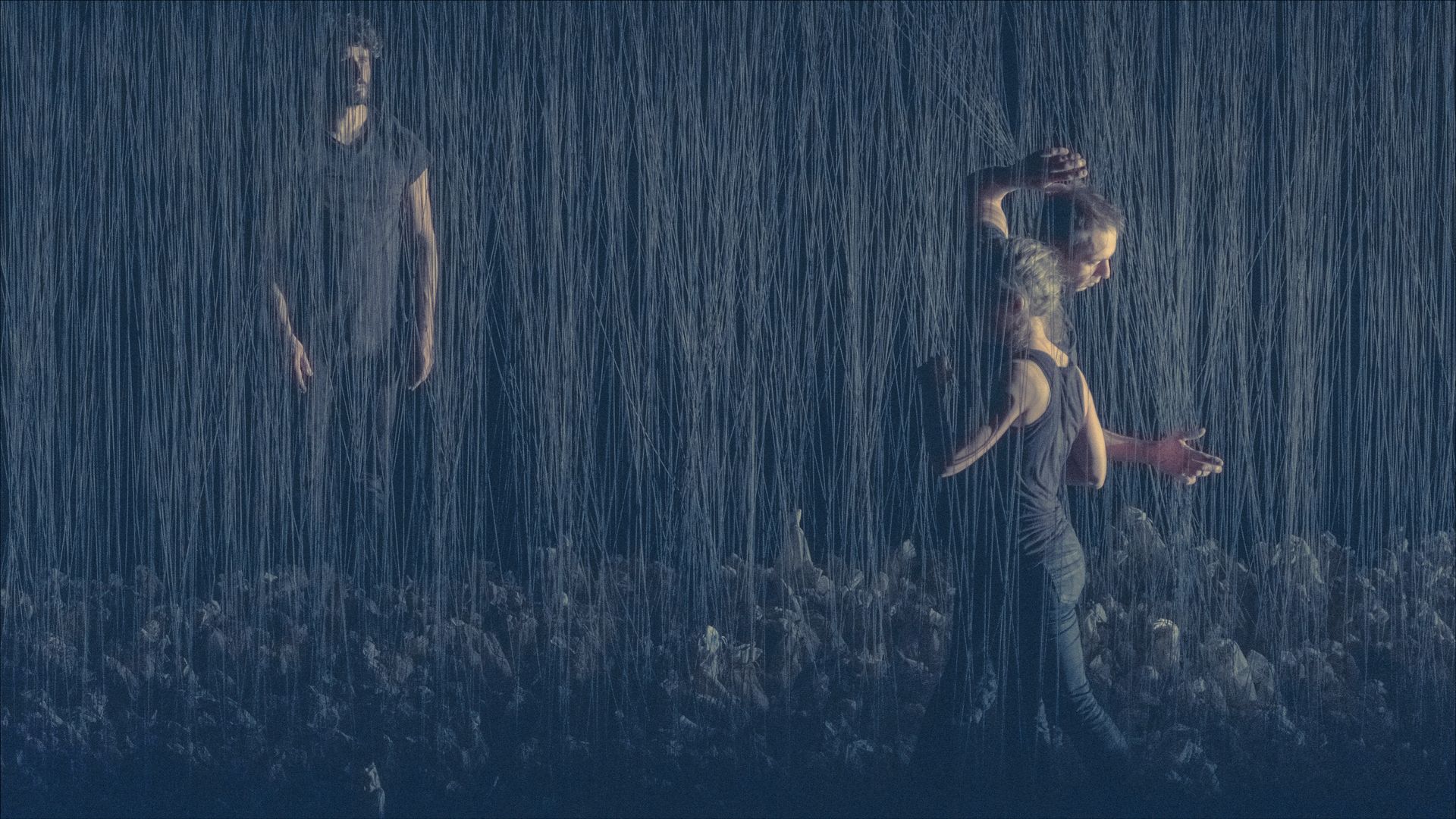 Person practicing martial arts in heavy rain, wielding a sword. Dark, blue-toned scene.