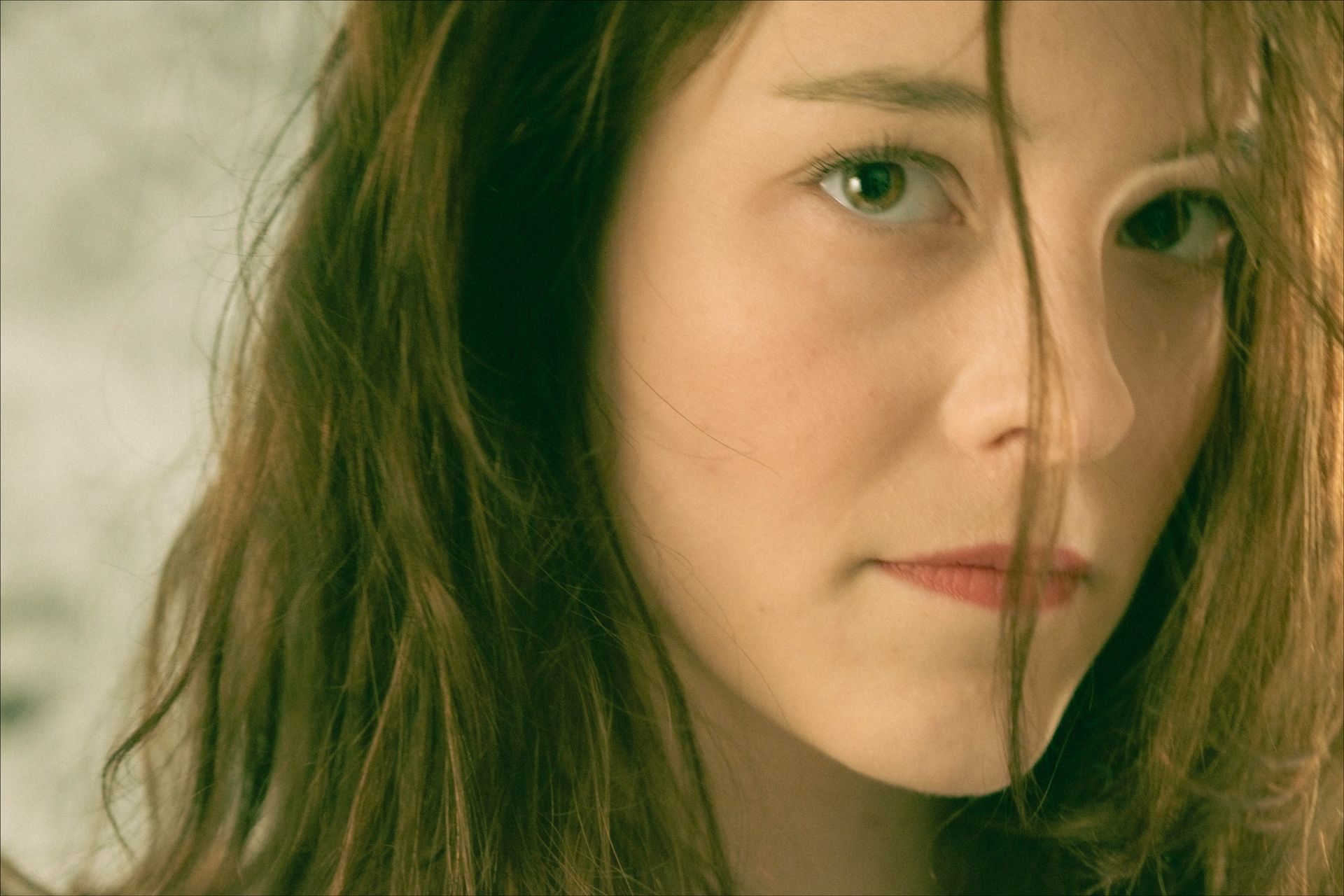 Woman with light brown hair, looking at the camera with a serious expression.