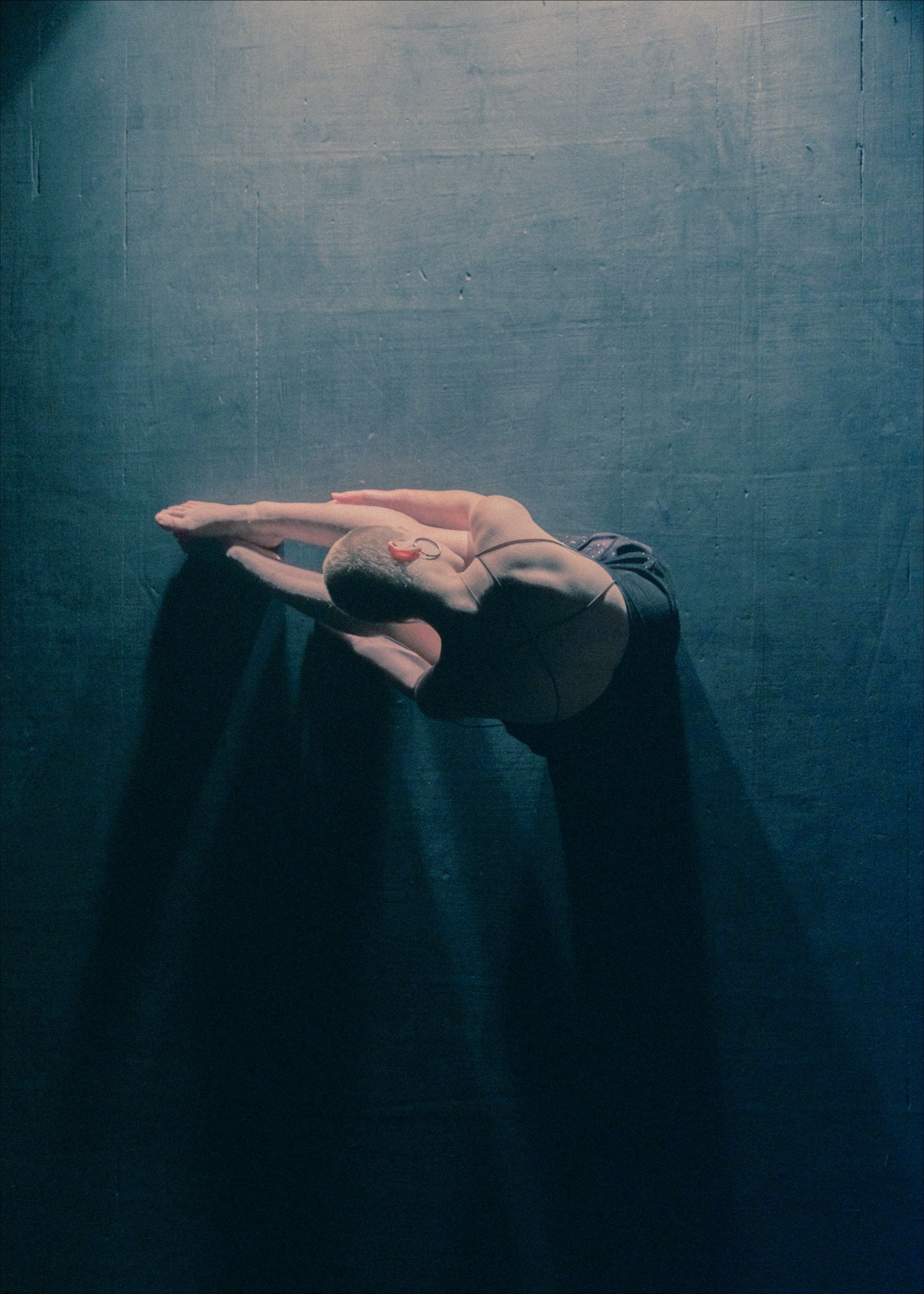 Hands clasped together, creating a shadowy arch against a dark, textured background.
