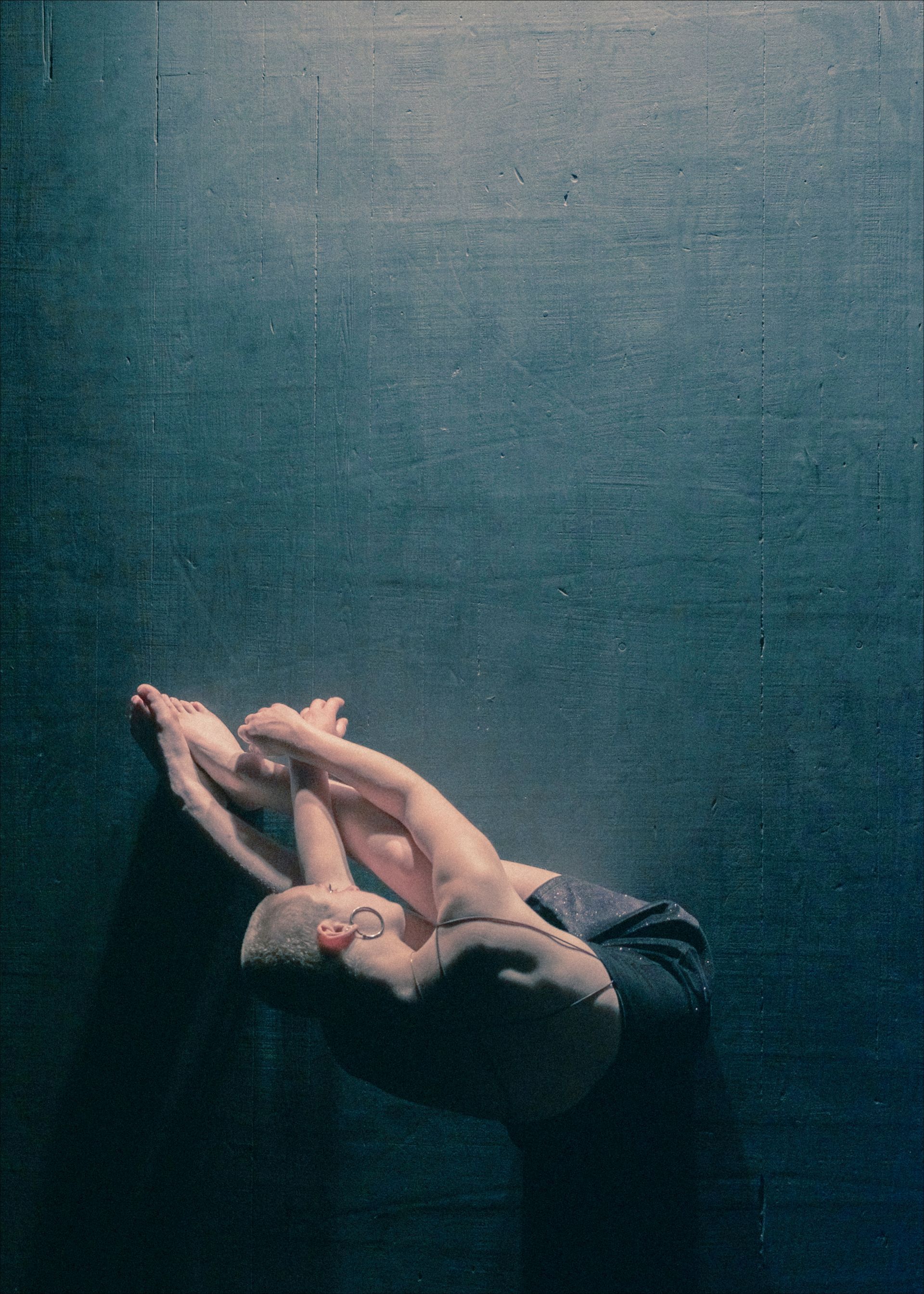 Hand cradling a nude infant against a dark blue background.