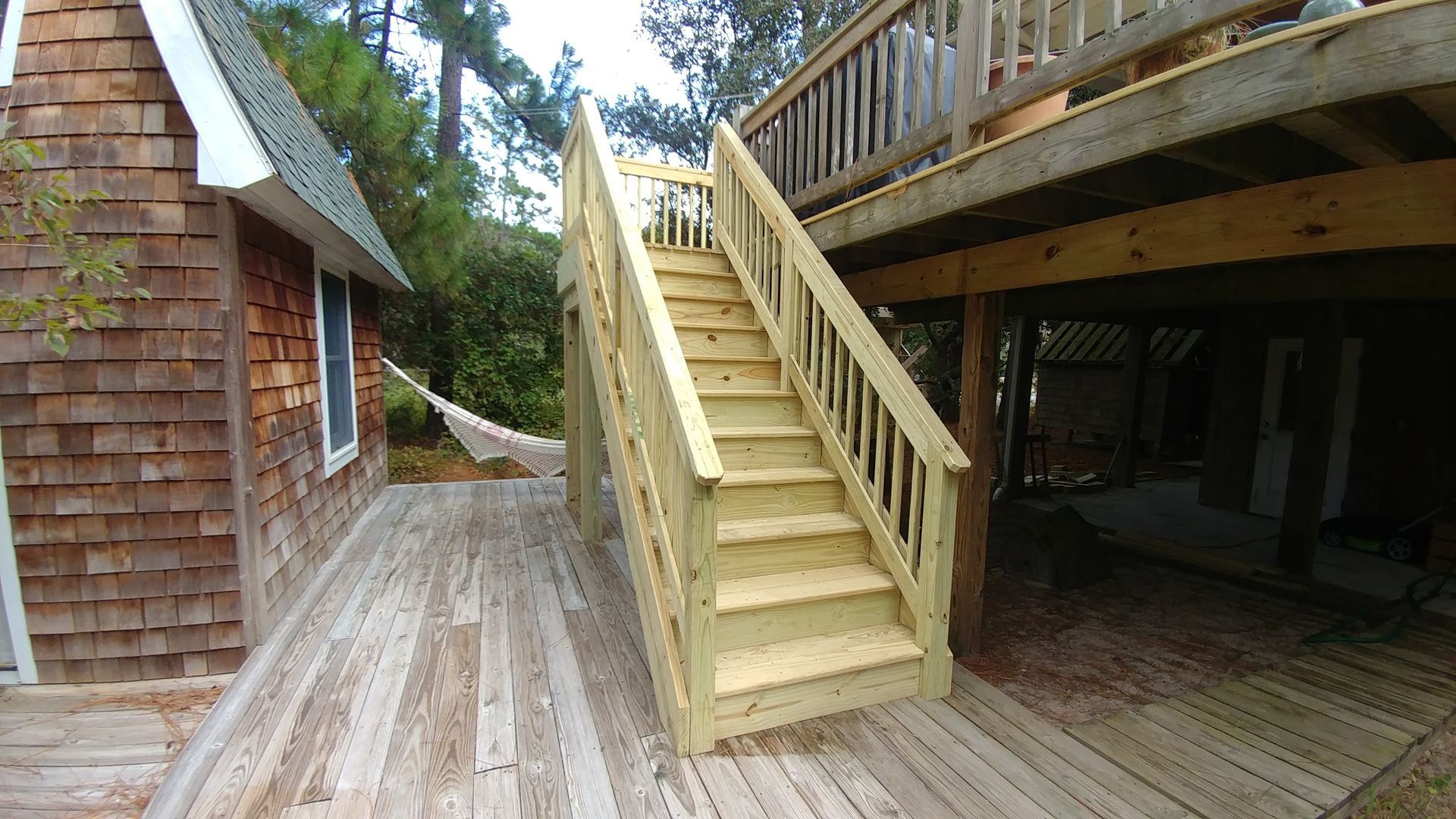 Wooden stairs leading to a second-story deck. The stairs are flanked by railings, and the surrounding decks