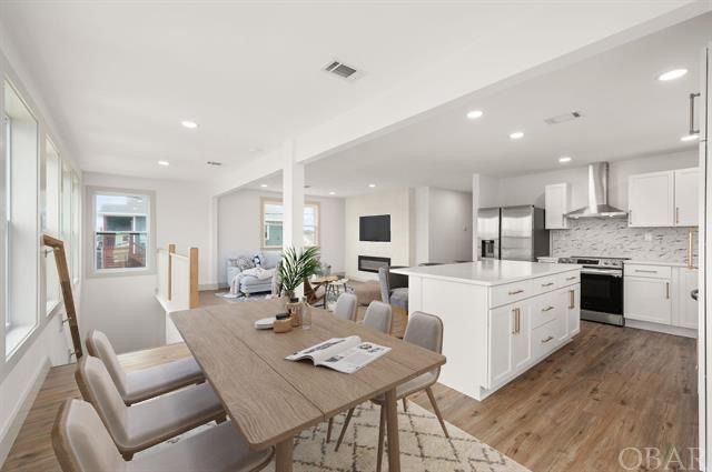 Open-concept kitchen and dining area with white cabinets, a large island, and a wooden dining table. 