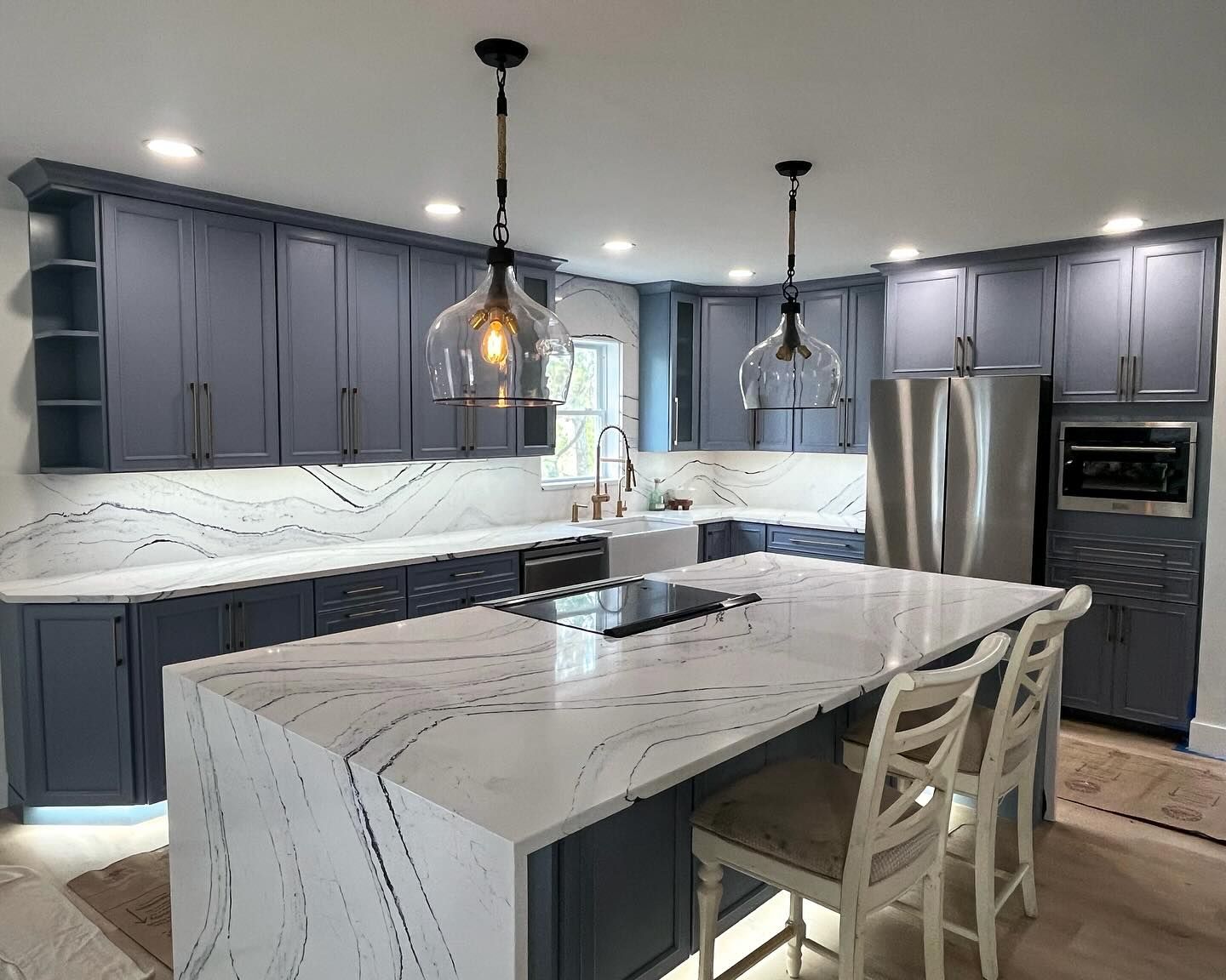 Modern kitchen with blue cabinets, white countertops, and a large island.