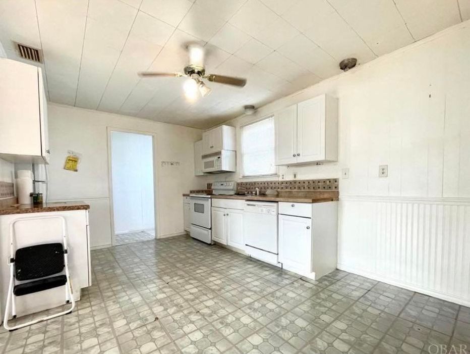 A white kitchen with white cabinets, appliances, and a ceiling f