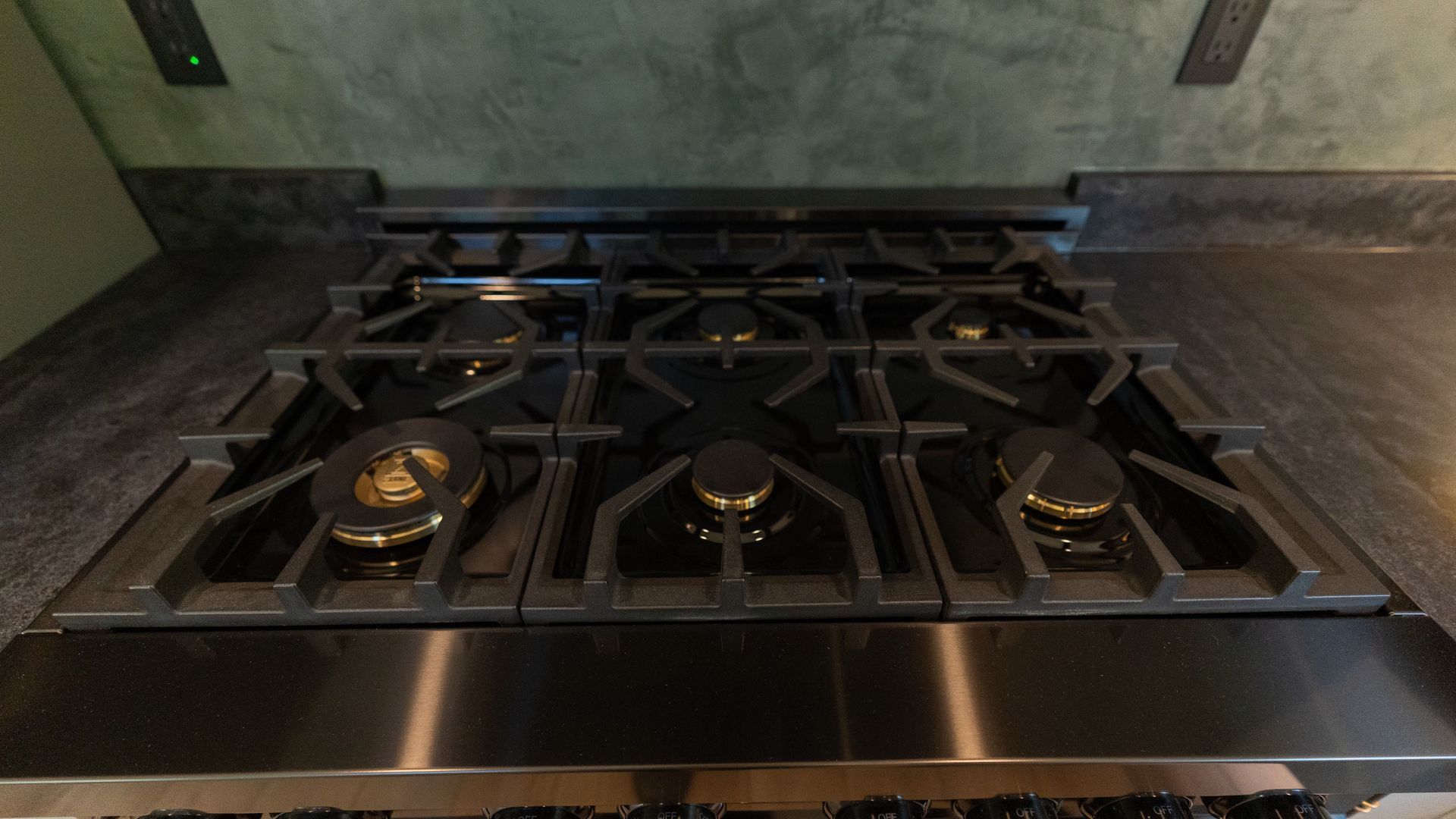 Gas stovetop with six burners lit and stainless steel detailing.
