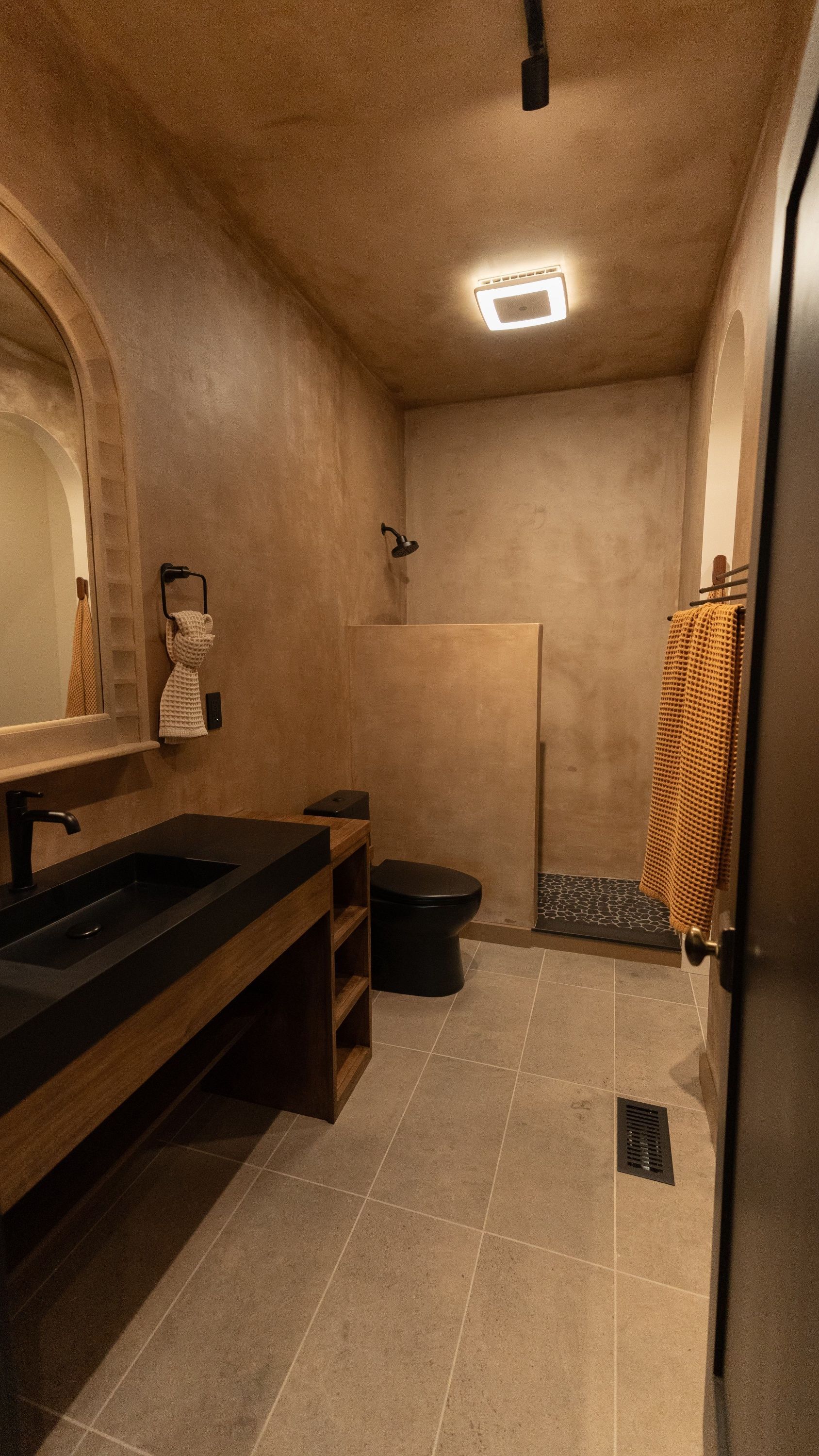 Bathroom with dark sink, black toilet, and textured walls.