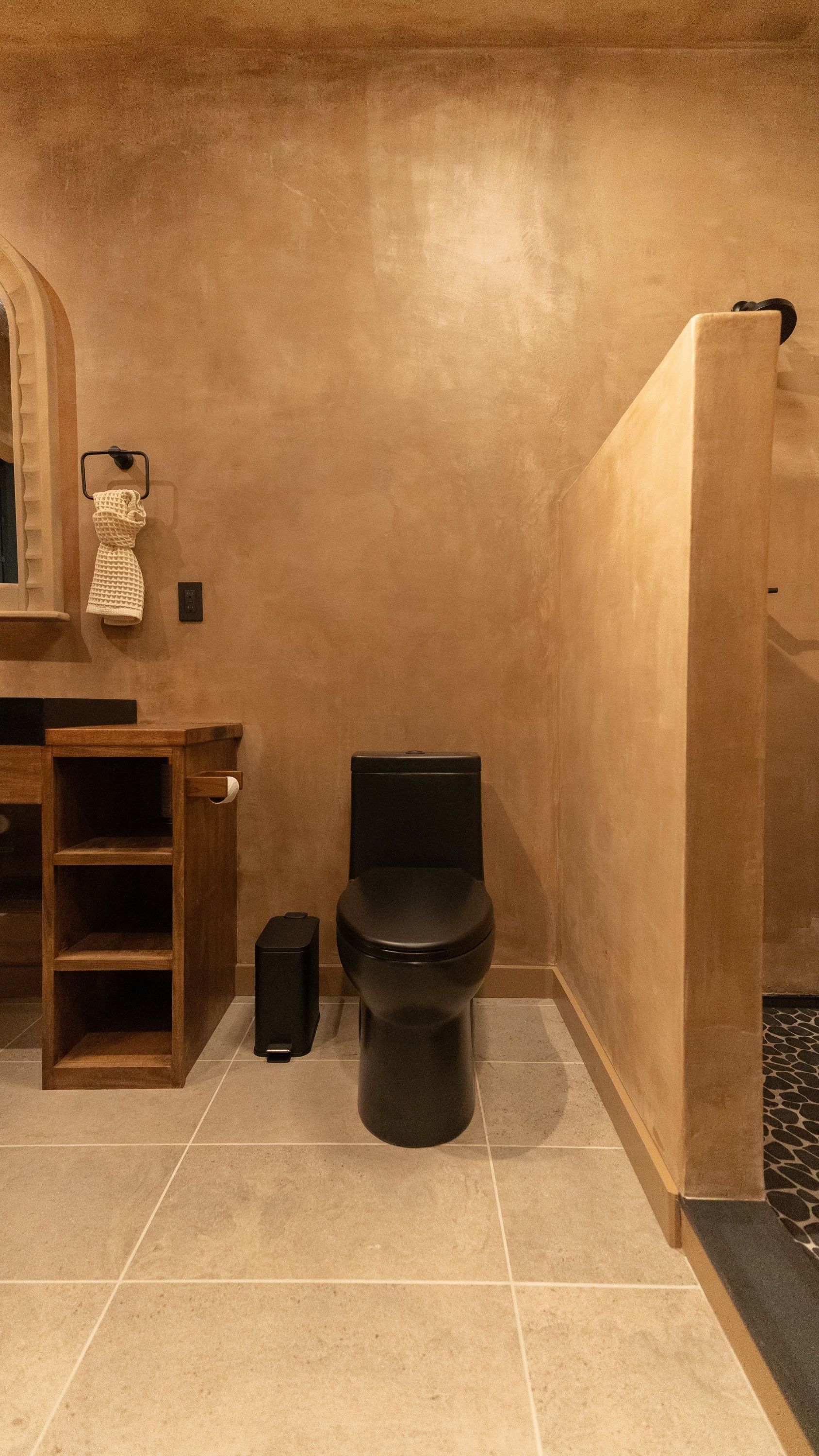 Bathroom with black toilet, neutral walls, wooden vanity, and walk-in shower.