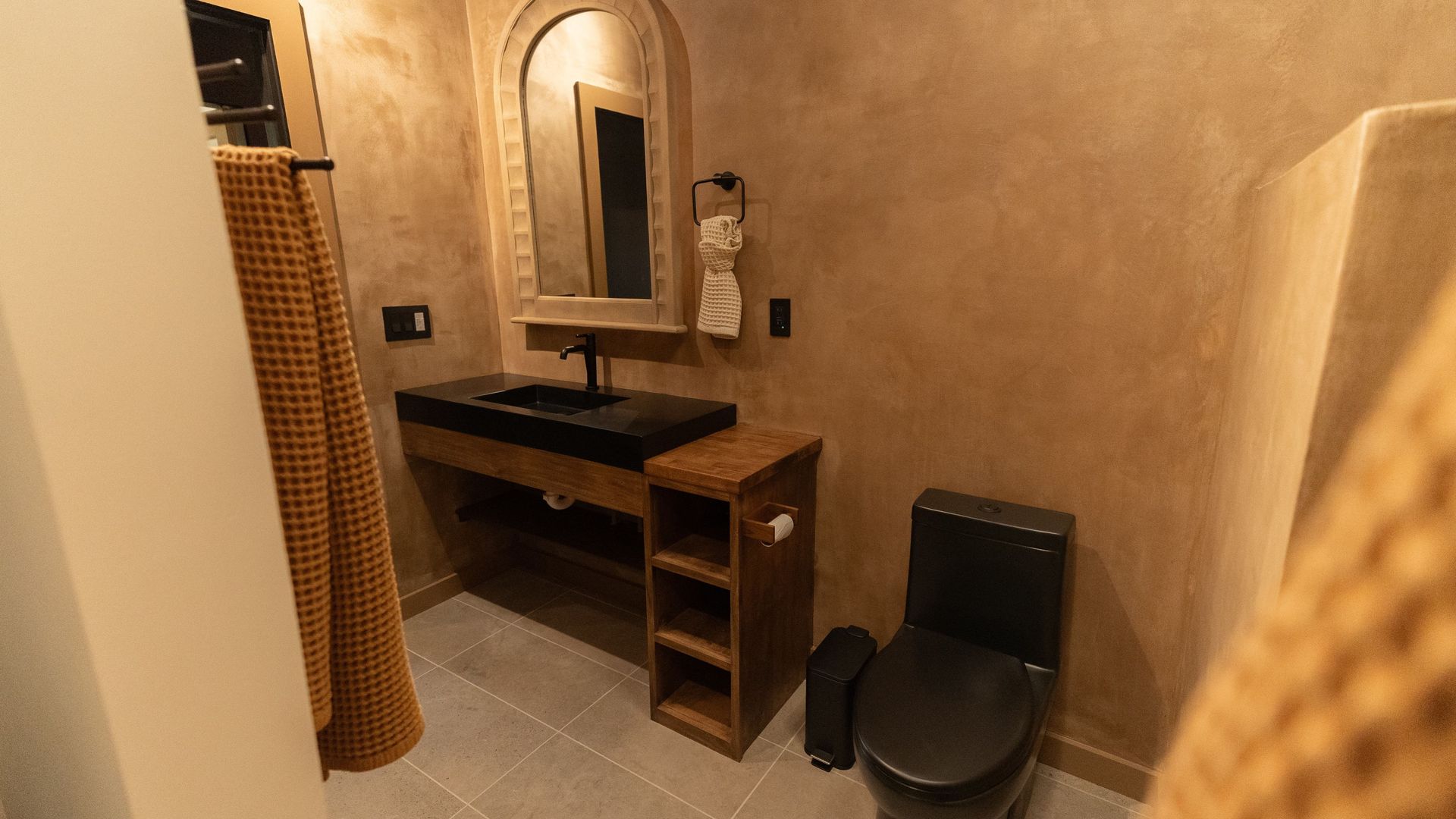 Bathroom with tan walls, black fixtures, and a wooden vanity.
