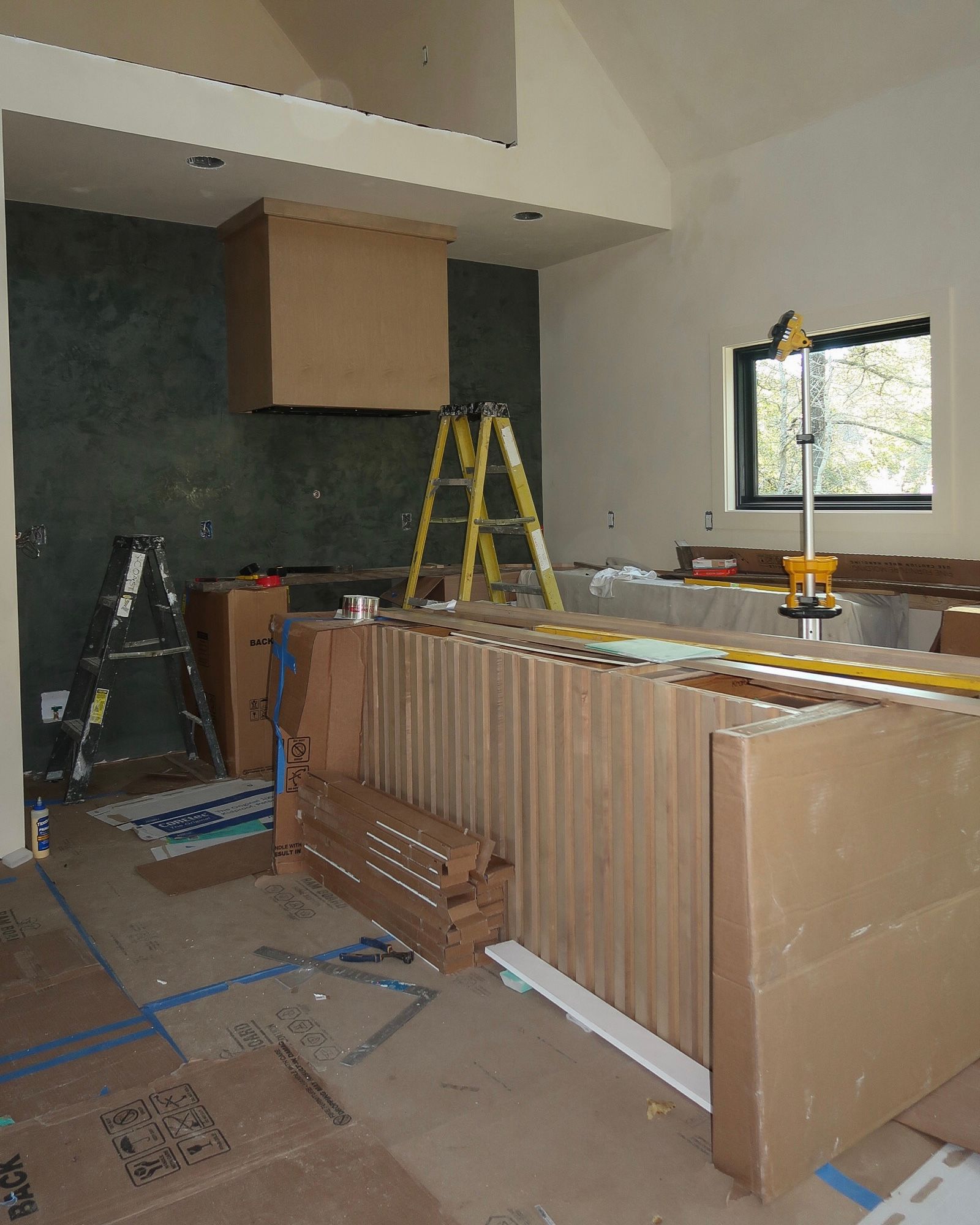 Kitchen remodel in progress. Cardboard boxes, tools, and a ladder are visible.