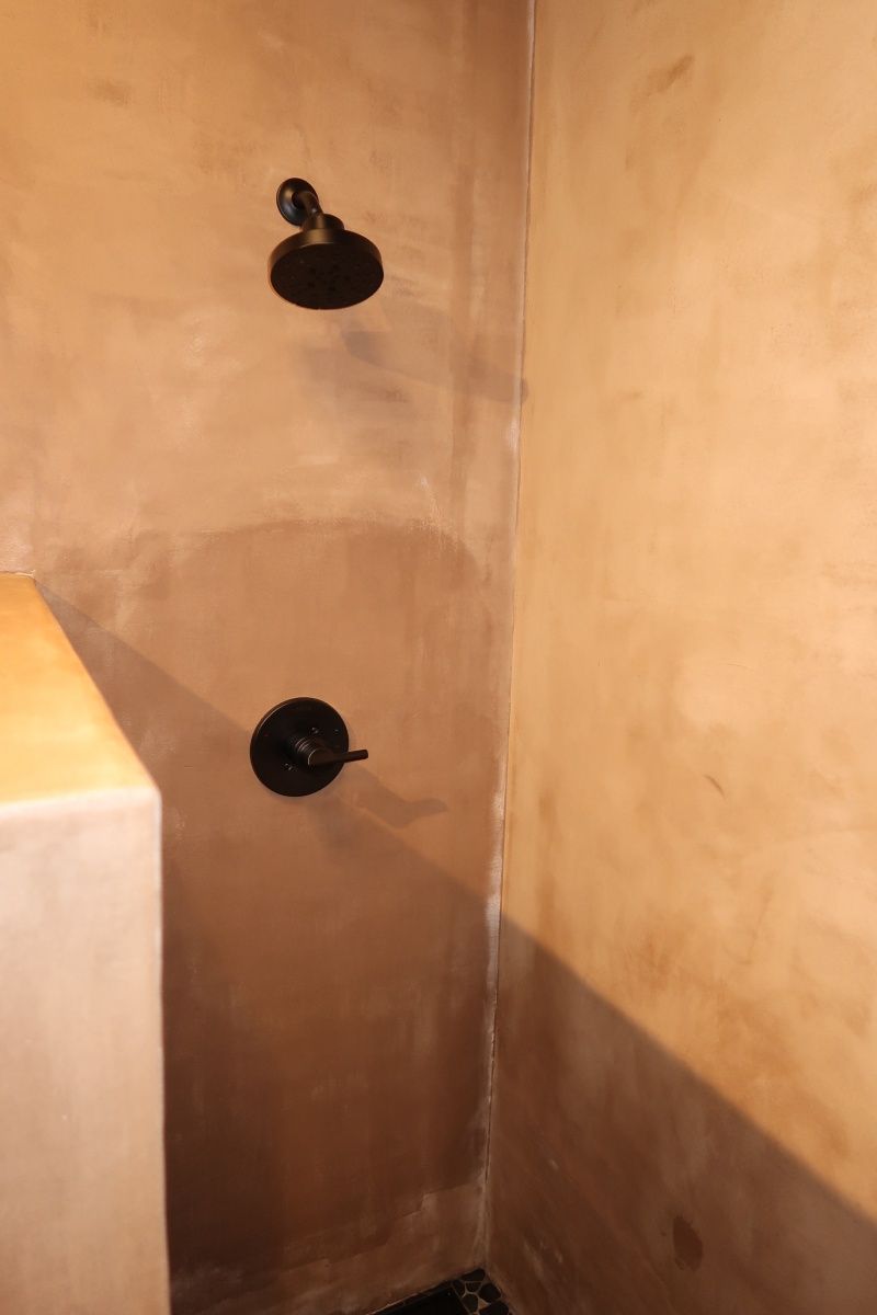 Dark shower fixtures on tan plaster walls.