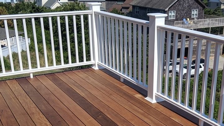 Wooden deck with white railing overlooking a residential neighborhood.