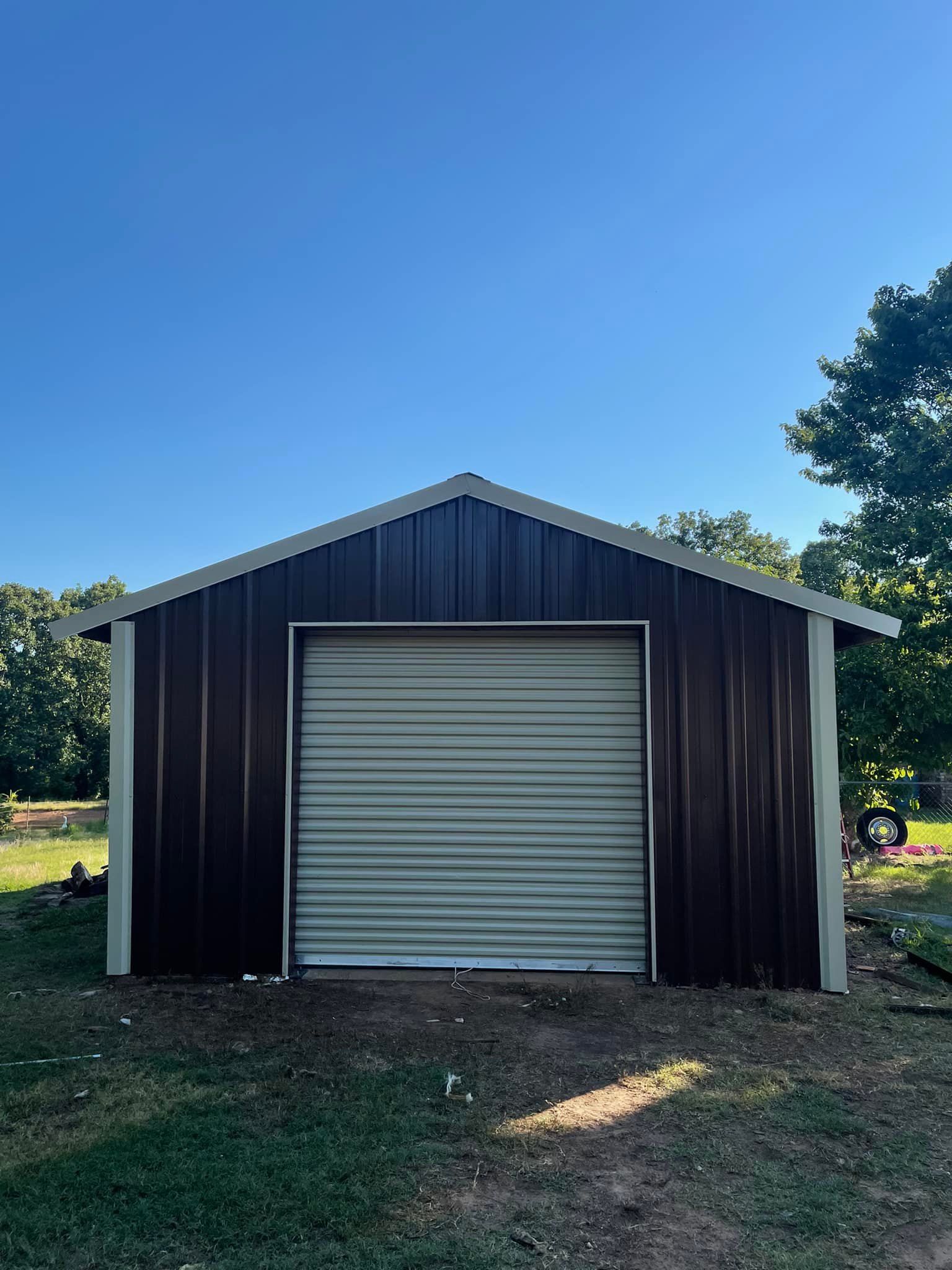 Brown metal storage shed with a roll-up door against a blue sky.