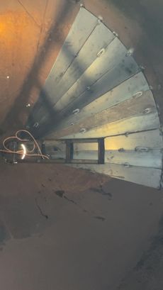 Inside a metal structure: fan-like metal sheets welded together, creating a spiral with a rectangular opening in the center.