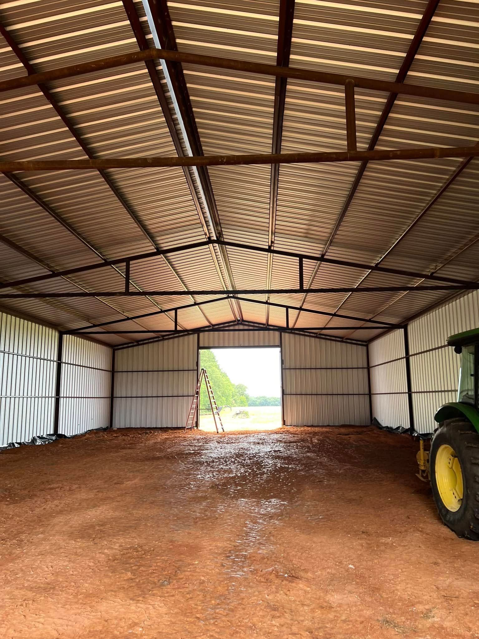 Inside a metal barn, a red dirt floor leads to an open doorway. Sunlight streams through the roof. A tractor sits on the right.