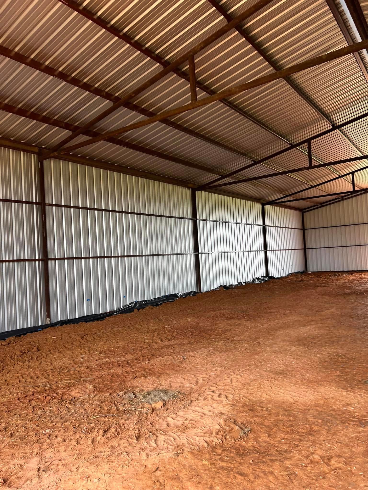 Empty metal shed with dirt floor and corrugated metal walls and ceiling.