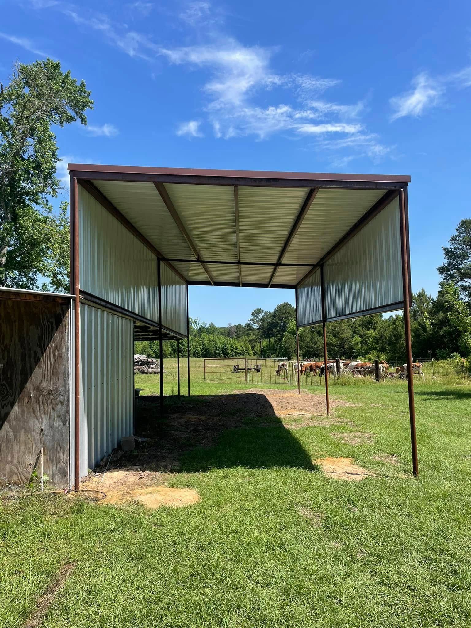 Open metal shed with a brown frame in a grassy field under a blue sky.