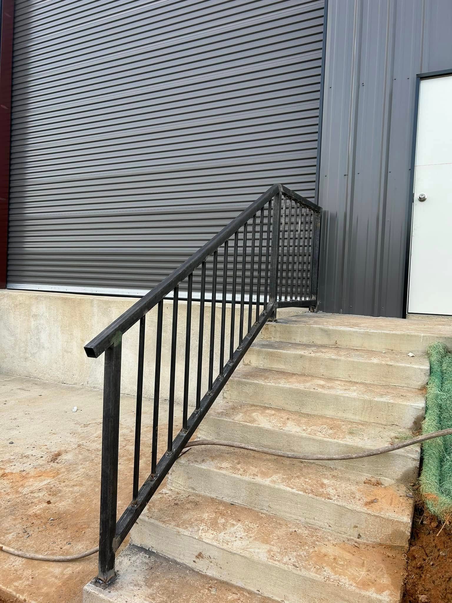 Concrete steps with black metal handrail leading up to a building entrance.