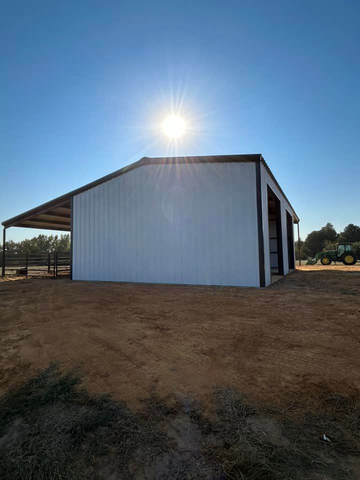 White metal barn with black trim under a bright sun.