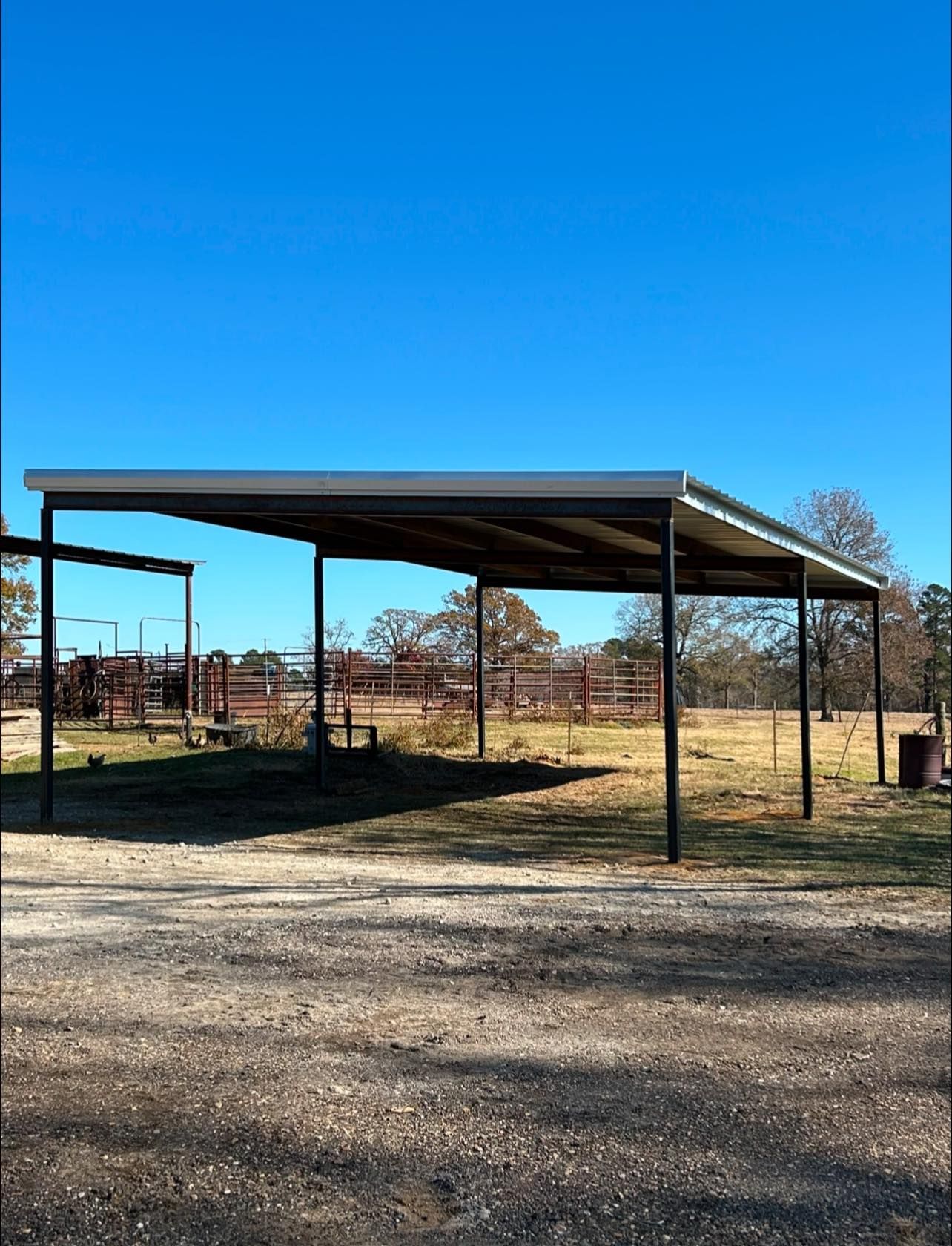 A metal carport with a clear blue sky background. It's in a rural setting.